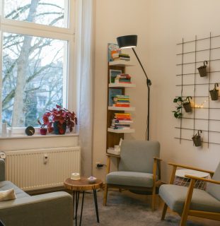 Gemütliche Leseecke mit Sesseln, Bücherregal und Pflanzen am Fenster