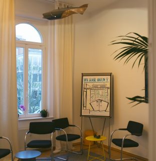 Seminarraum mit Stühlen, Flipchart und hohem Altbaufenster