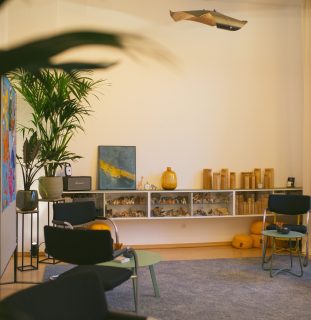 Sideboard mit Holzfiguren für die Aufstellungsarbeit, darüber ein blau-goldenes Gemälde